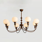 Eight-light Clérachic chandelier switched on, with a wide spread of curved bronze arms and ribbed globes against a pale grey backdrop.