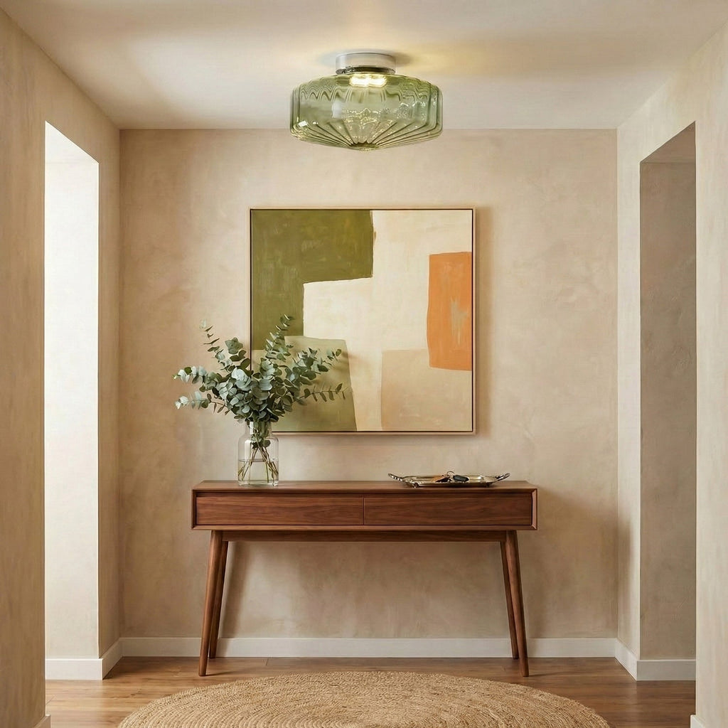 This Clérachic ceiling light in green ribbed glass hangs in a hallway with a walnut console, a eucalyptus stem and a framed print.