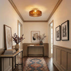 Brown Clérachic ceiling light lit warm in a panelled hallway, with a patterned runner and framed prints on the walls.