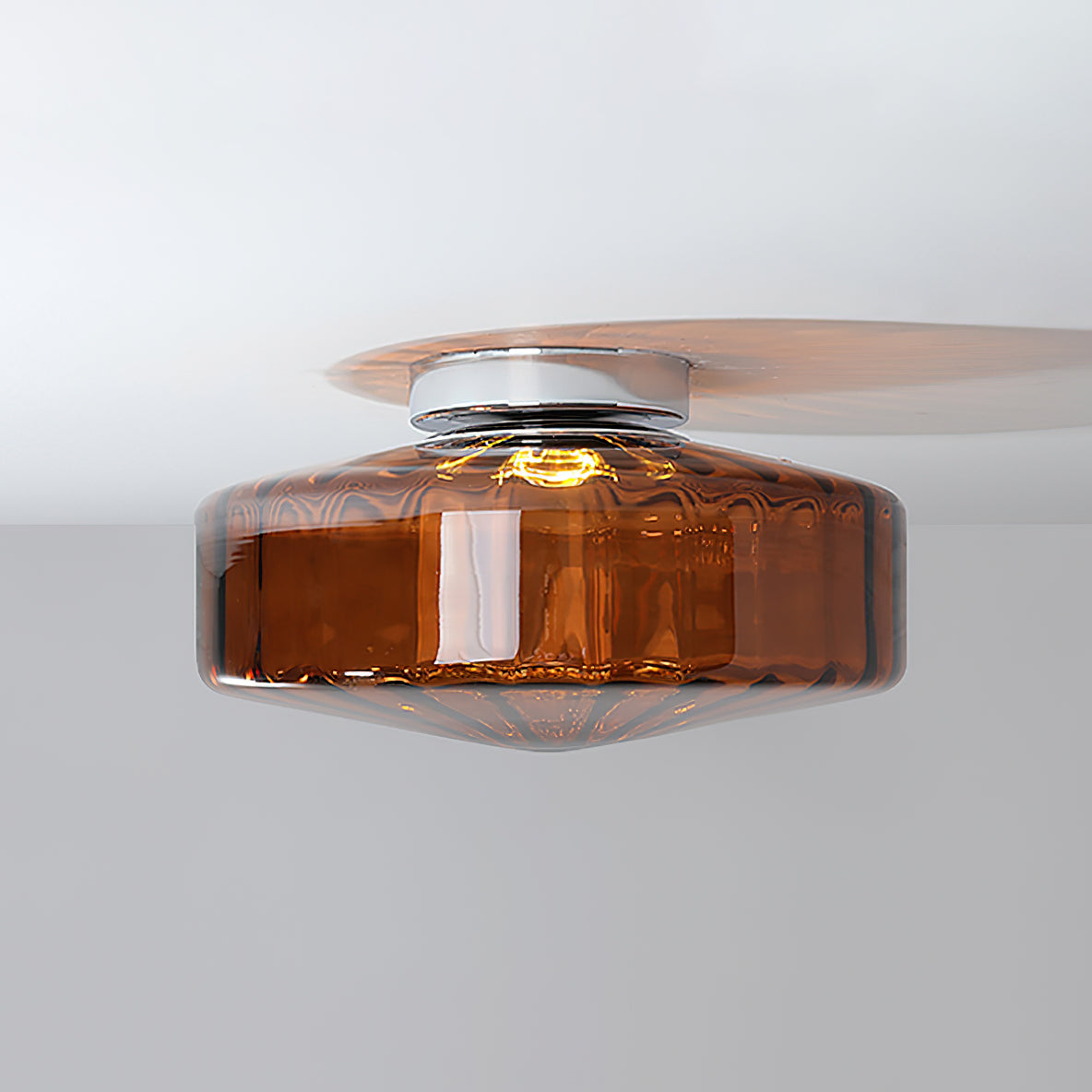 Side view of this Clérachic ceiling light in brown ribbed glass, with its chrome plate and the shadow it casts on a white ceiling.