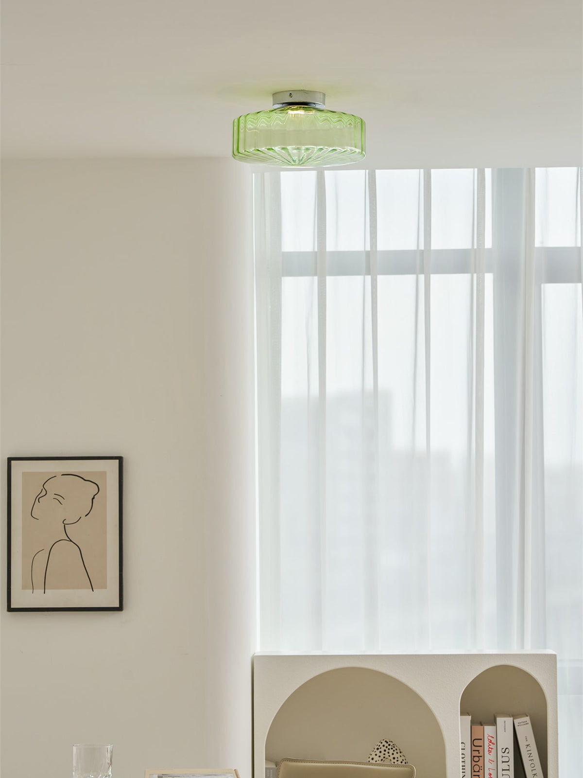 This Clérachic ceiling light in green ribbed glass seen from across the room, with a framed print and an arched shelf below.