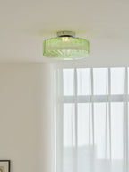 Closer view of this Clérachic ceiling light in green ribbed glass, lit on a white ceiling above sheer curtains.