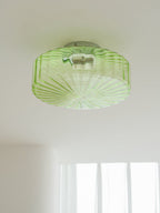 Green Clérachic ceiling light seen from below on a white ceiling, with fine ribs radiating across the glass.