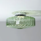 Green ribbed glass Clérachic ceiling light with a chrome plate, throwing a pale fan of light across a white ceiling.