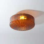 Underside of this Clérachic ceiling light in brown glass, with ribs radiating from the centre and the bulb glowing.