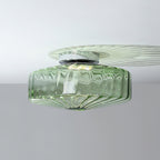 Green ribbed glass Clérachic ceiling light on a white ceiling, with a chrome plate and a pale fan of light above it.