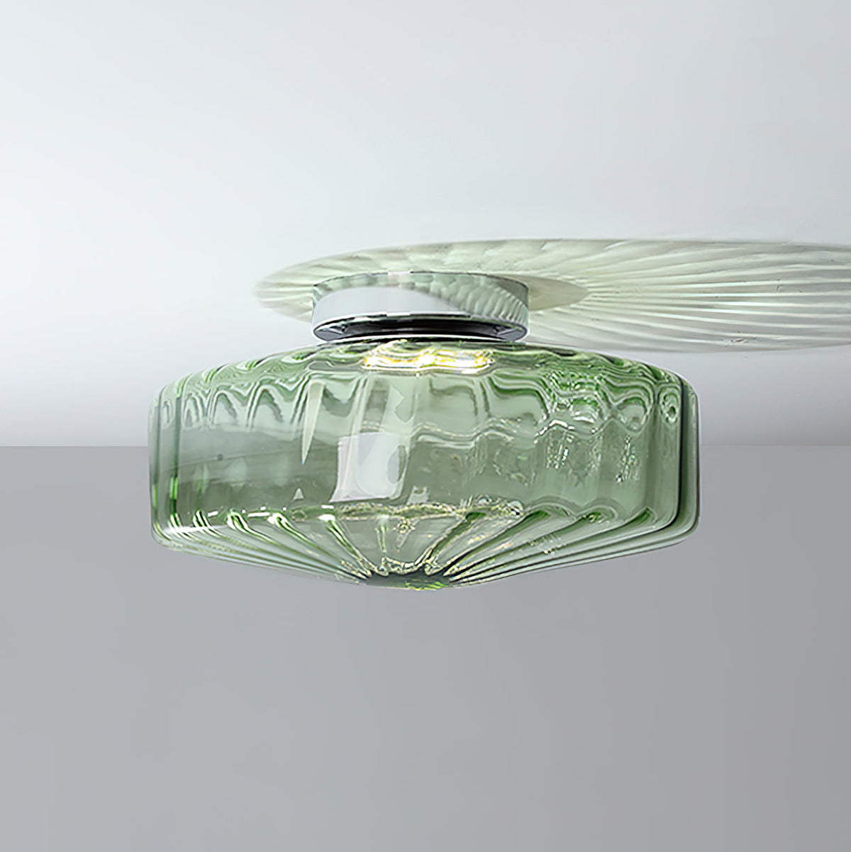 Green ribbed glass Clérachic ceiling light on a white ceiling, with a chrome plate and a pale fan of light above it.