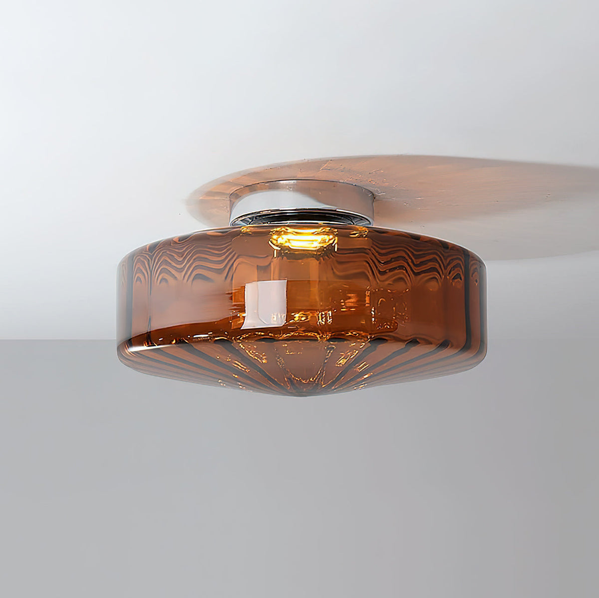 This Clérachic ceiling light in brown ribbed glass, switched on, with its bulb visible inside the dark amber shade.