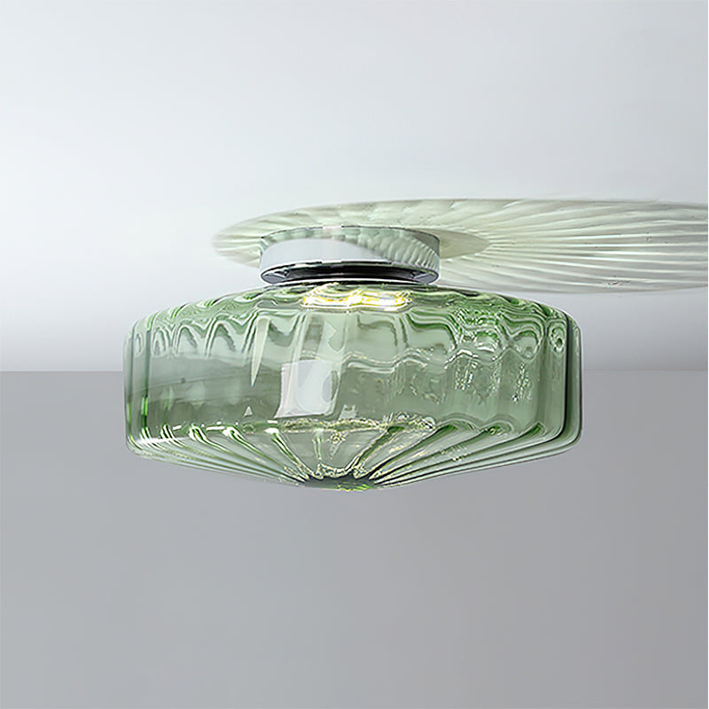 This Clérachic ceiling light in green glass, with a chrome plate and a faint fan of light across the white ceiling.