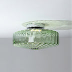 This Clérachic ceiling light in green glass, with a chrome plate and a faint fan of light across the white ceiling.