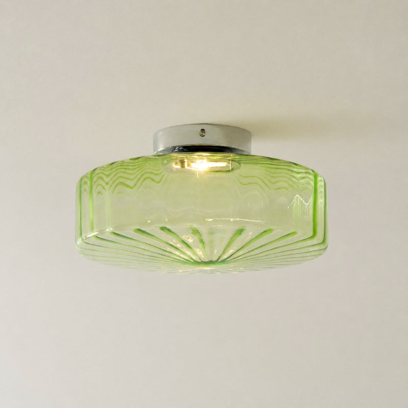 Front view of a green ribbed glass Clérachic ceiling light with a chrome ceiling plate and a bulb visible inside.