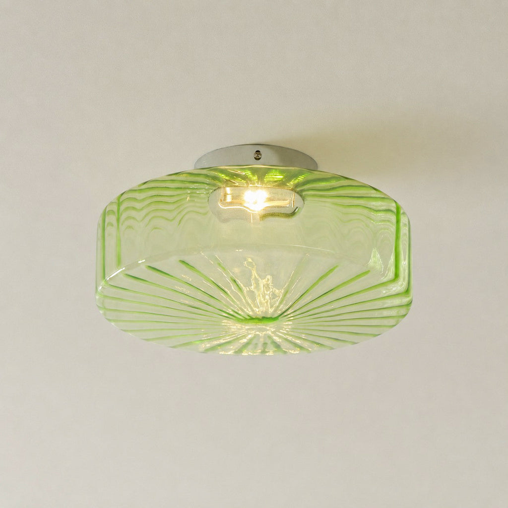 Green Clérachic ceiling light seen from below, with its ribbed underside radiating and a bulb showing through the glass.