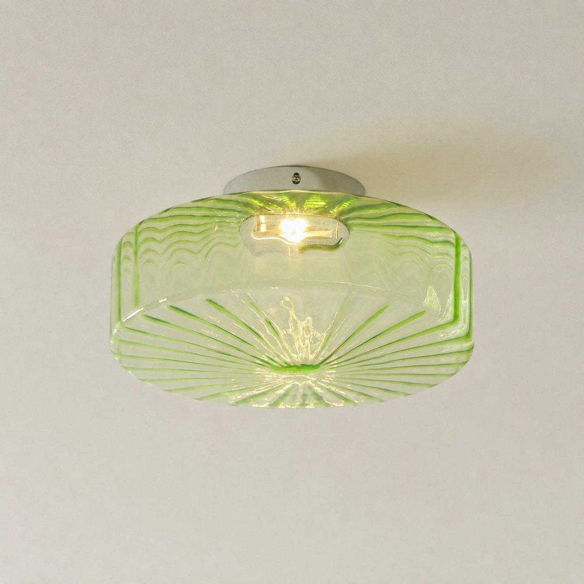 Green Clérachic ceiling light seen from below, with its ribbed underside radiating and a bulb showing through the glass.