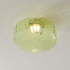 Close view of the green ribbed glass shade on this Clérachic ceiling light, with its bulb glowing inside.
