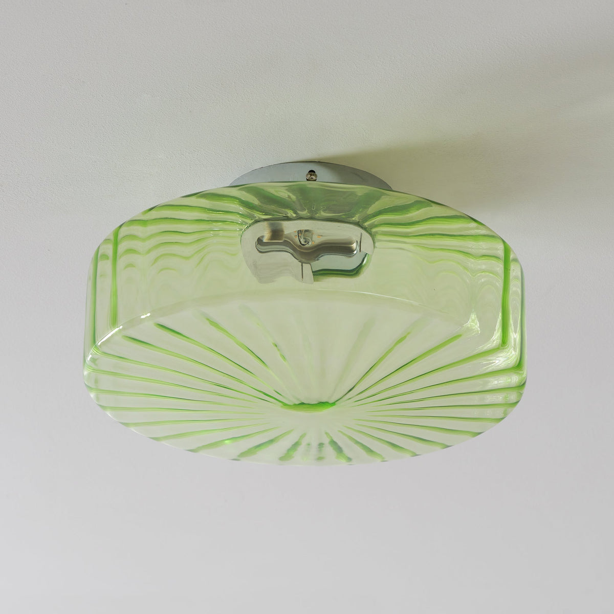 Underside of this Clérachic ceiling light, its green glass with long ribs and a chrome fitting reflected in the shade.
