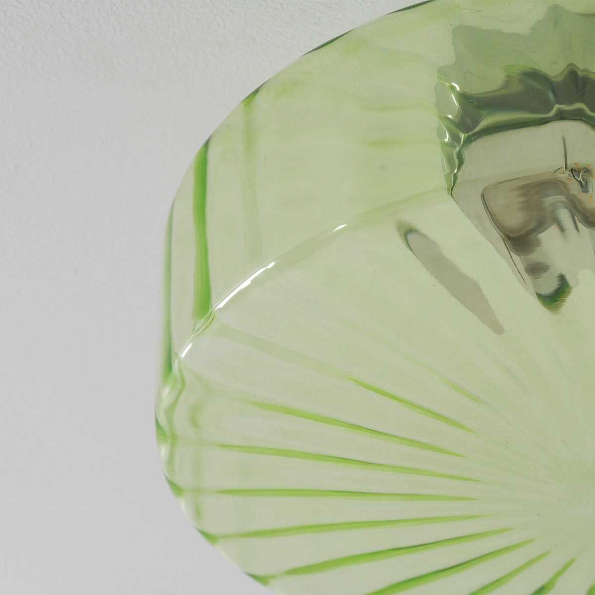 Cropped close view of the green glass ribs and chrome fitting on the underside of this Clérachic ceiling light.