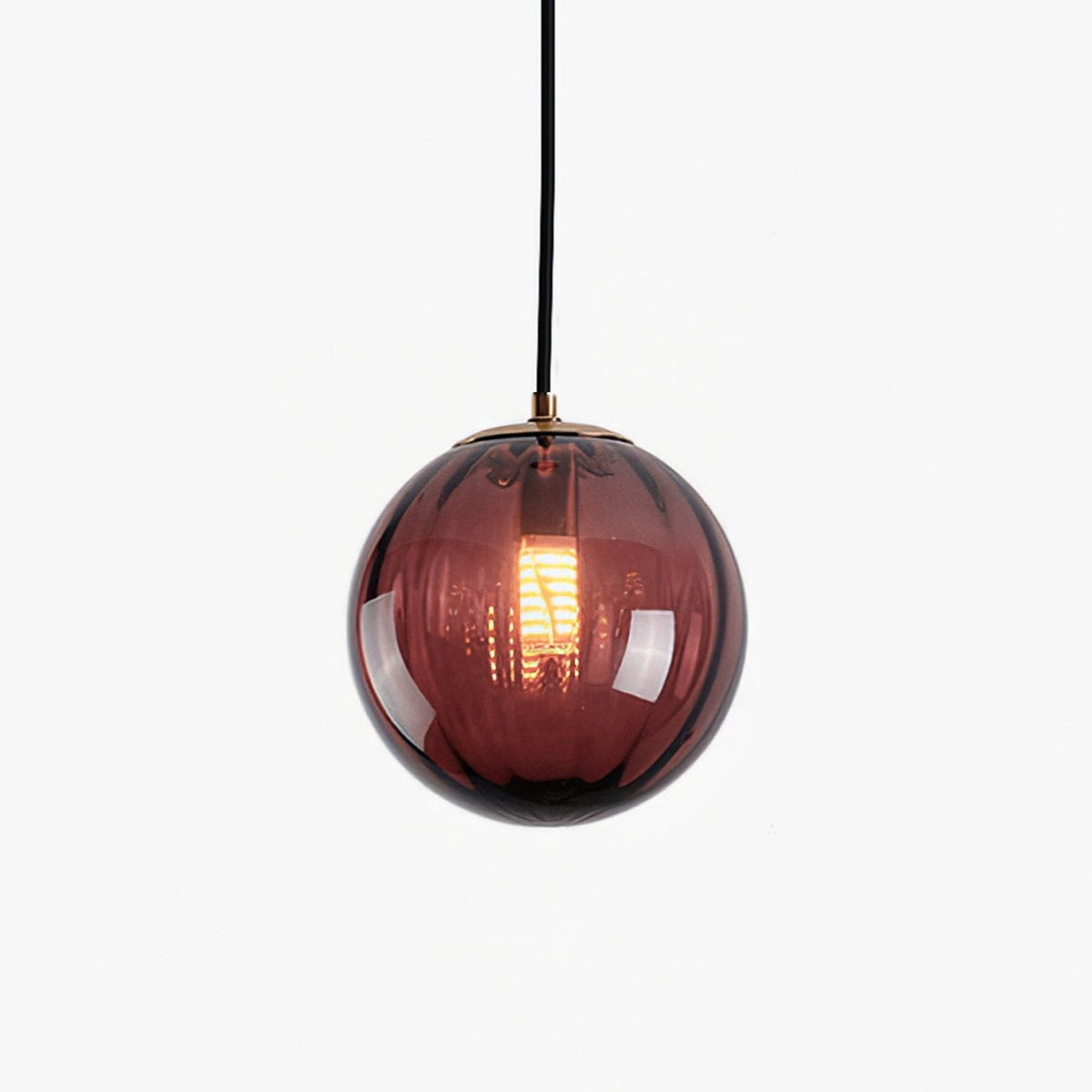 Wine red ribbed glass globe pendant from Clérachic on a white backdrop, a filament bulb glowing inside.