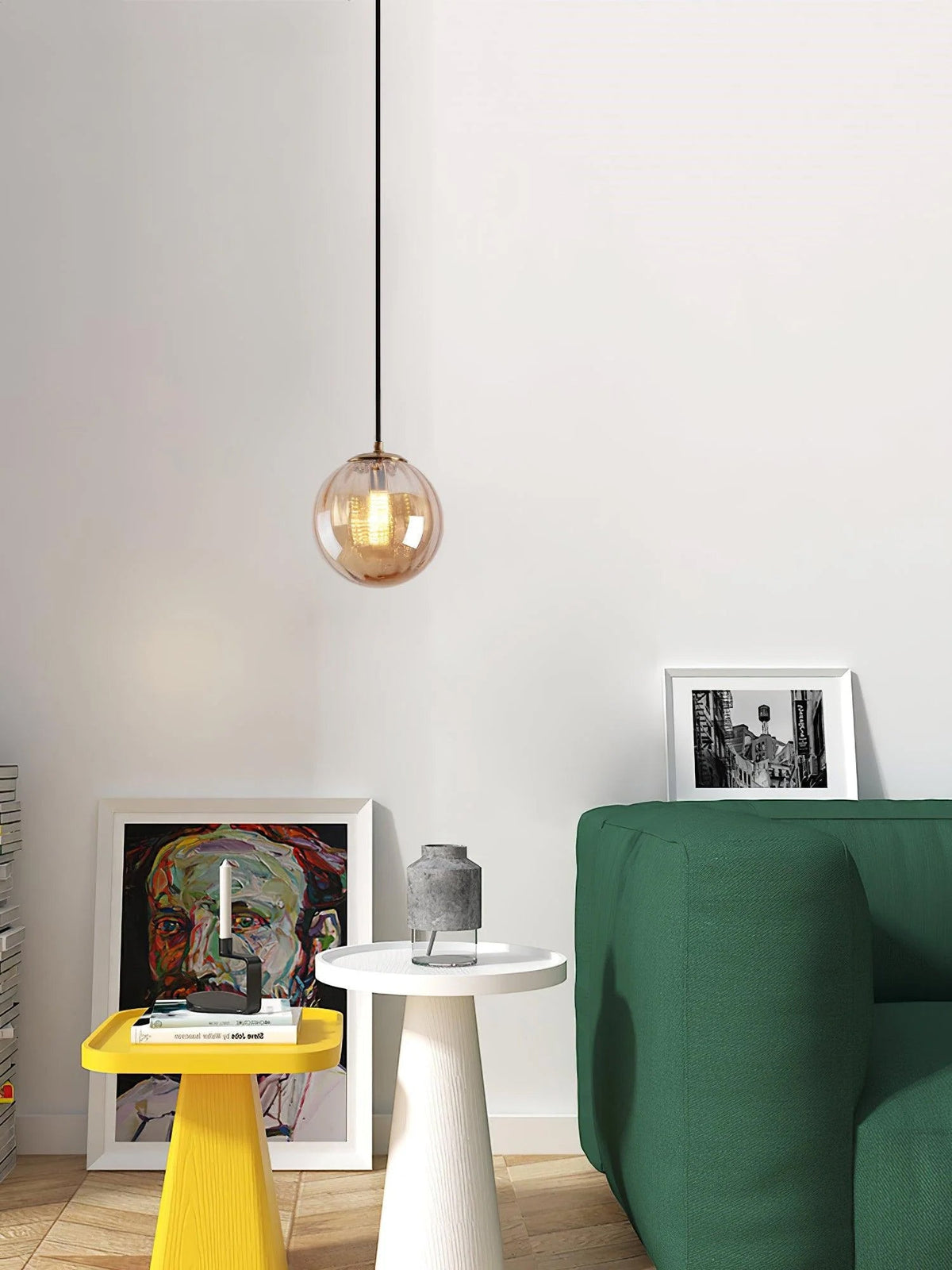 Small amber Clérachic glass pendant in a white room with a green sofa, a yellow stool and framed art.