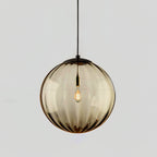 Amber ribbed glass Clérachic pendant with a black cap, a filament bulb lit inside, on a grey backdrop.