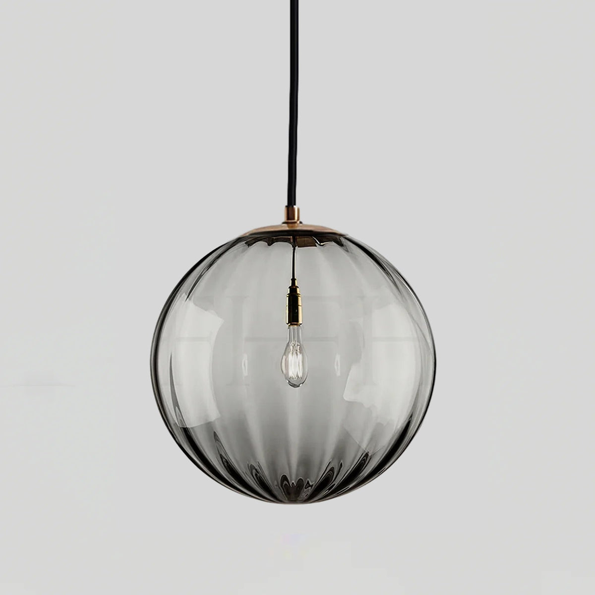 Smoke grey ribbed glass Clérachic pendant with a gold-toned cap, an unlit bulb visible inside.