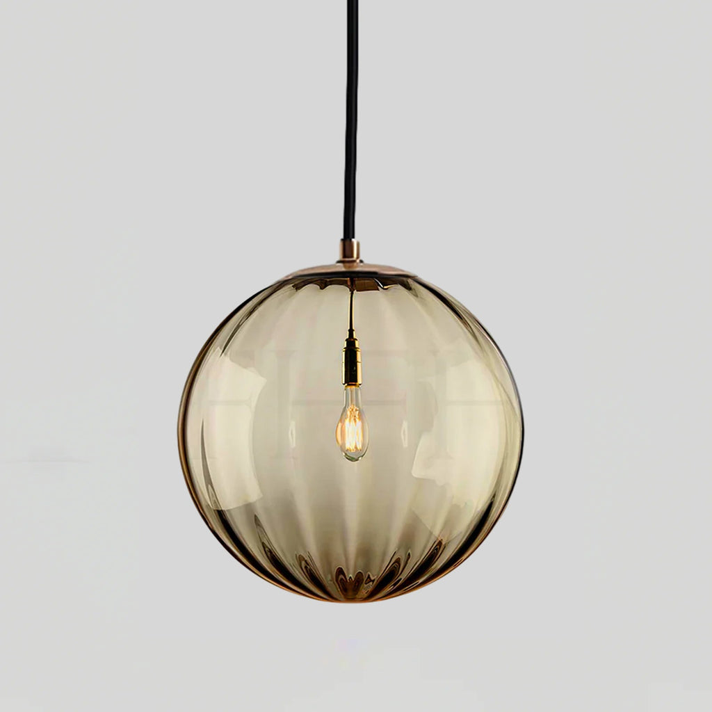 Amber ribbed glass Clérachic pendant with a gold-toned cap, shown against a light grey backdrop.