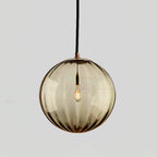 Amber ribbed glass Clérachic pendant with a gold-toned cap, shown against a light grey backdrop.