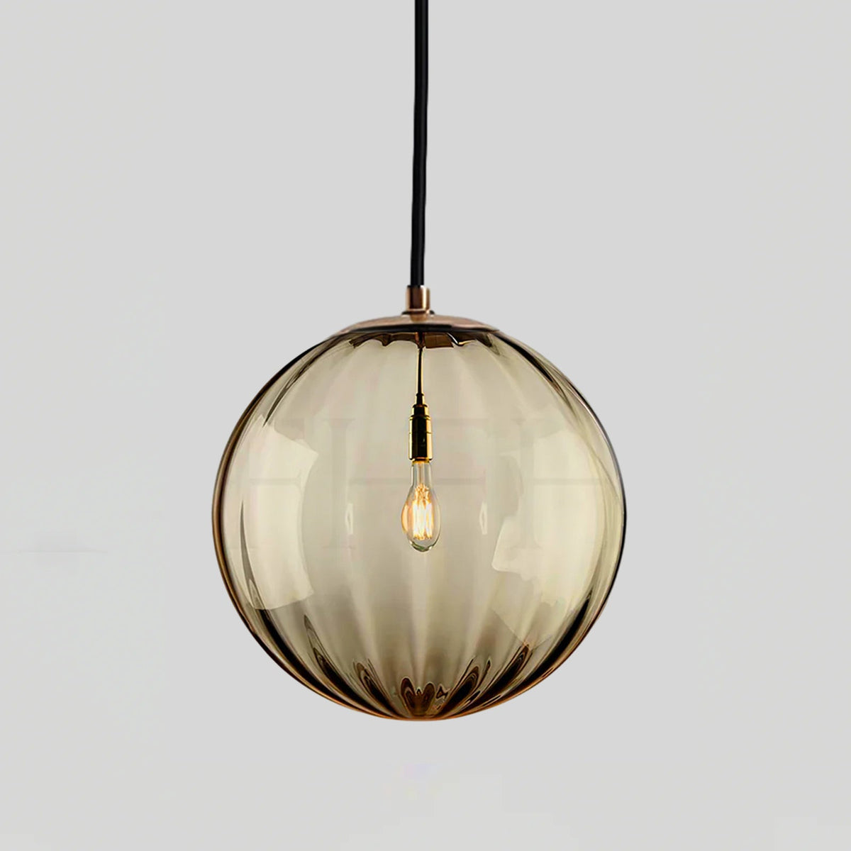 Amber ribbed glass Clérachic pendant with a gold-toned cap, shown against a light grey backdrop.