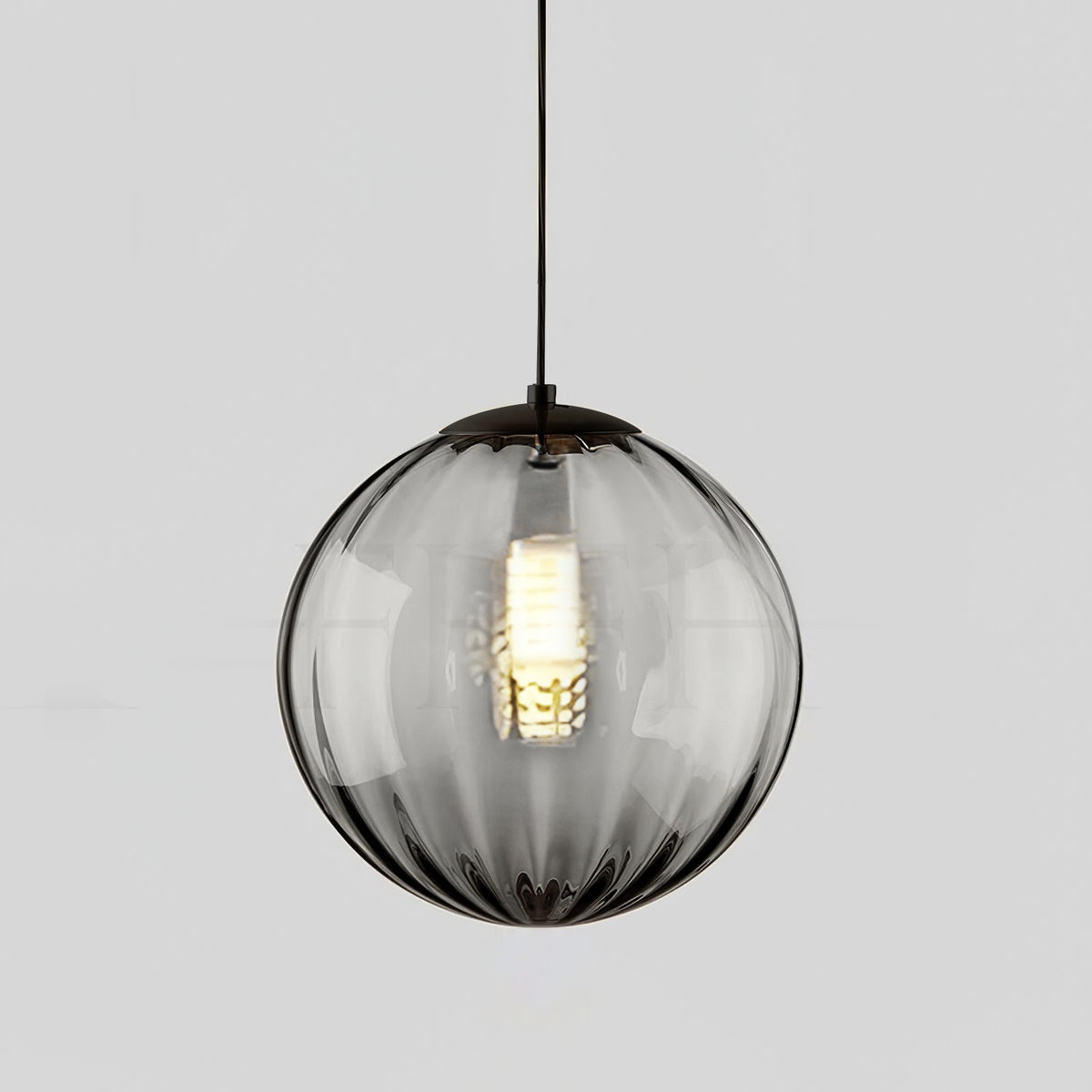 Smaller smoke grey Clérachic glass pendant with a black cap, a bright bulb glowing at its centre.