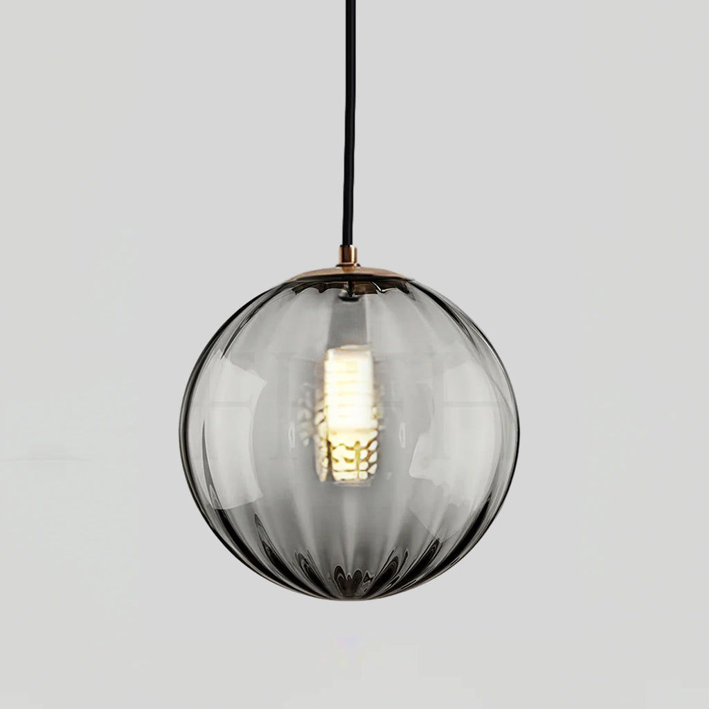 Smaller smoke grey Clérachic glass pendant with a gold-toned cap and a lit bulb inside.