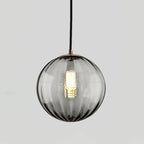Smaller smoke grey Clérachic glass pendant with a gold-toned cap and a lit bulb inside.