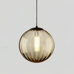 Smaller amber Clérachic ribbed glass pendant with a black cap and a glowing bulb inside.