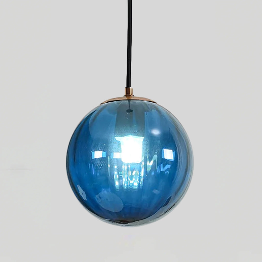 Blue Clérachic glass globe pendant with a gold-toned cap, a bright bulb showing through the glass.