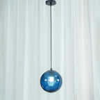 Close view of a blue Clérachic glass pendant and its black canopy, with a sheer curtain behind.
