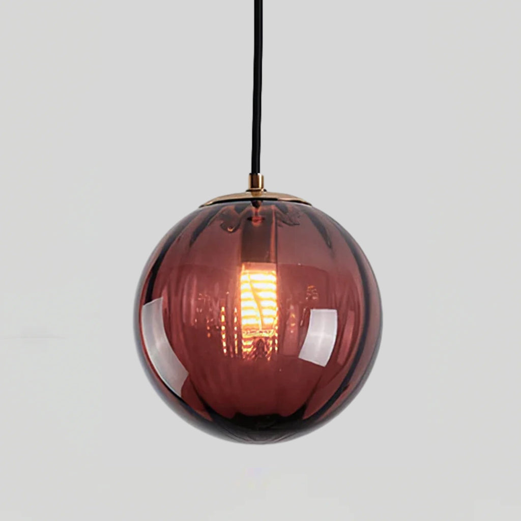 Close view of a wine red Clérachic glass globe with fine vertical ribs and a glowing filament bulb.