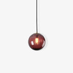 Small wine red Clérachic ribbed glass pendant on an off-white backdrop, its bulb glowing warmly.