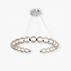 Open ring of ribbed light grey glass beads lit from within, hung on fine wires from a chrome canopy, this Clérachic pendant on white.