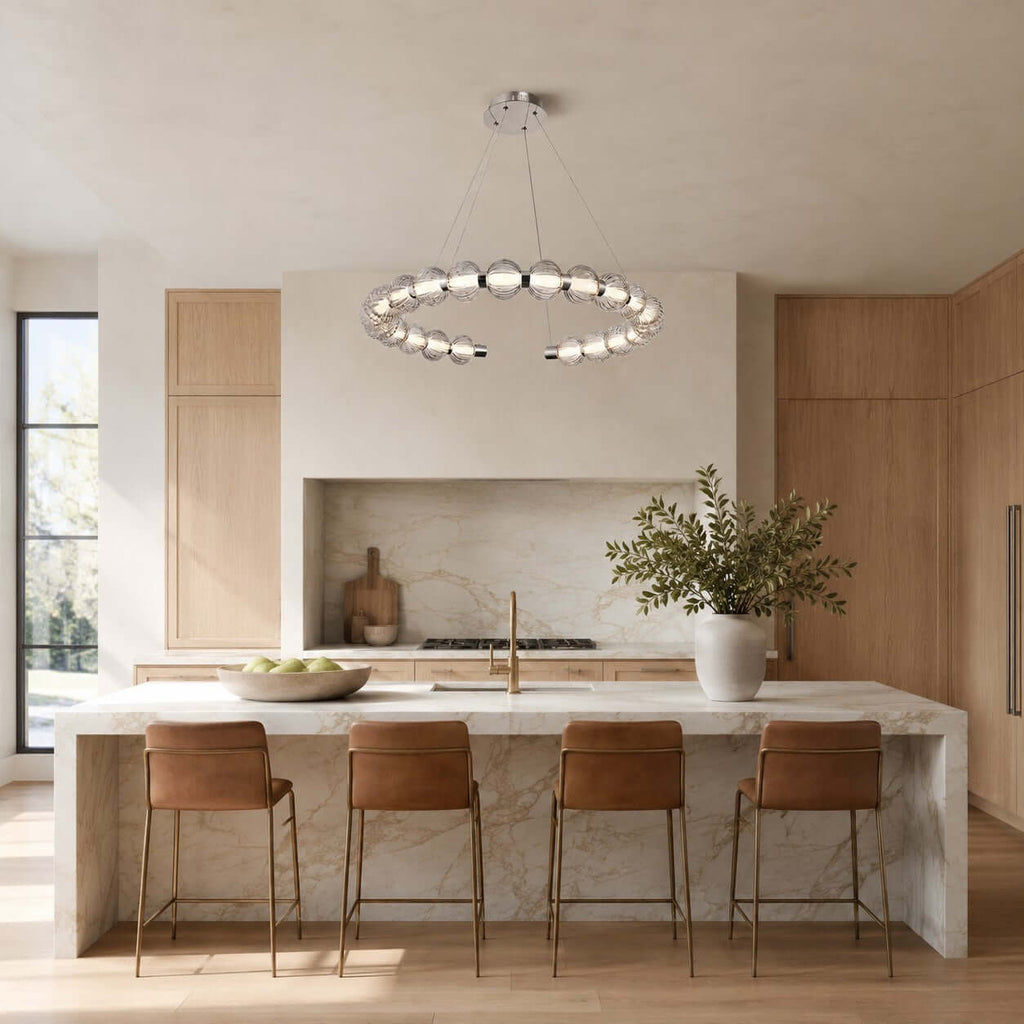 This Clérachic pendant floats above a stone kitchen island with four tan leather stools and a pale oak cabinet wall behind.