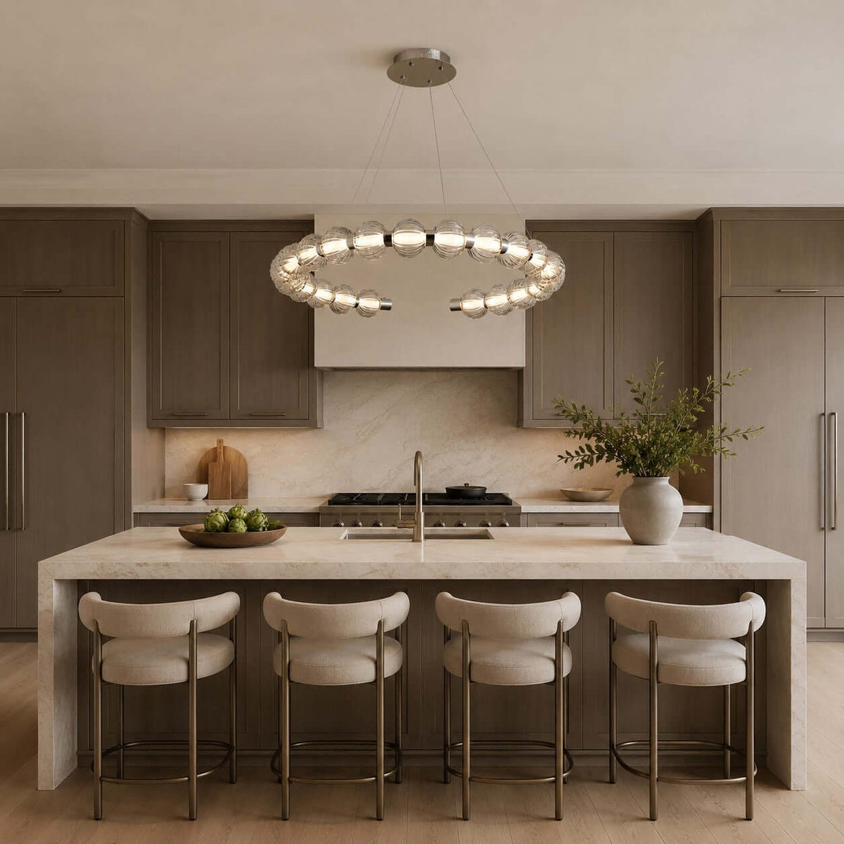This Clérachic pendant hangs over a long stone island with four cream bar stools, in a kitchen of warm brown cabinets.