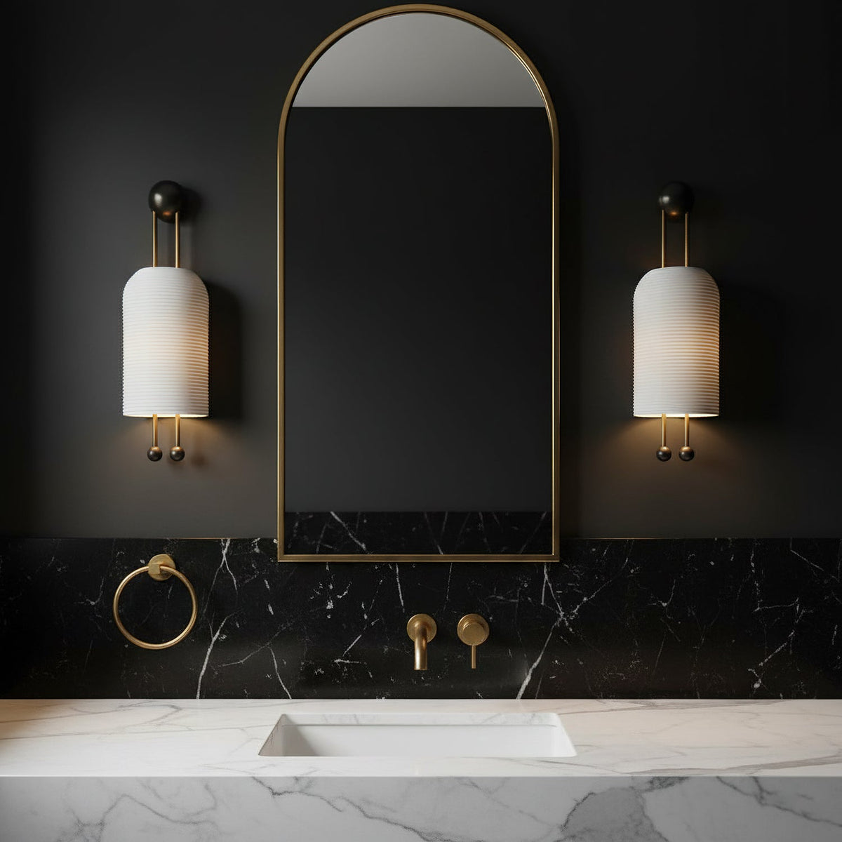 Pair of Clérachic ribbed wall lights flanking a tall arched mirror above a black marble backsplash and white marble basin top.