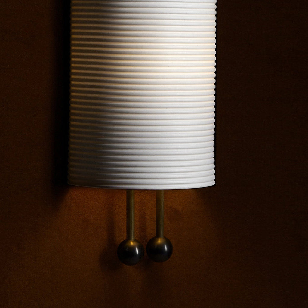 Close view of the horizontal ribbing on the lower shade and the two gold rods ending in black balls on this Clérachic wall light.