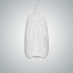 The tall oval wire-cage Clérachic pendant in white, lit on a pale grey-blue backdrop.