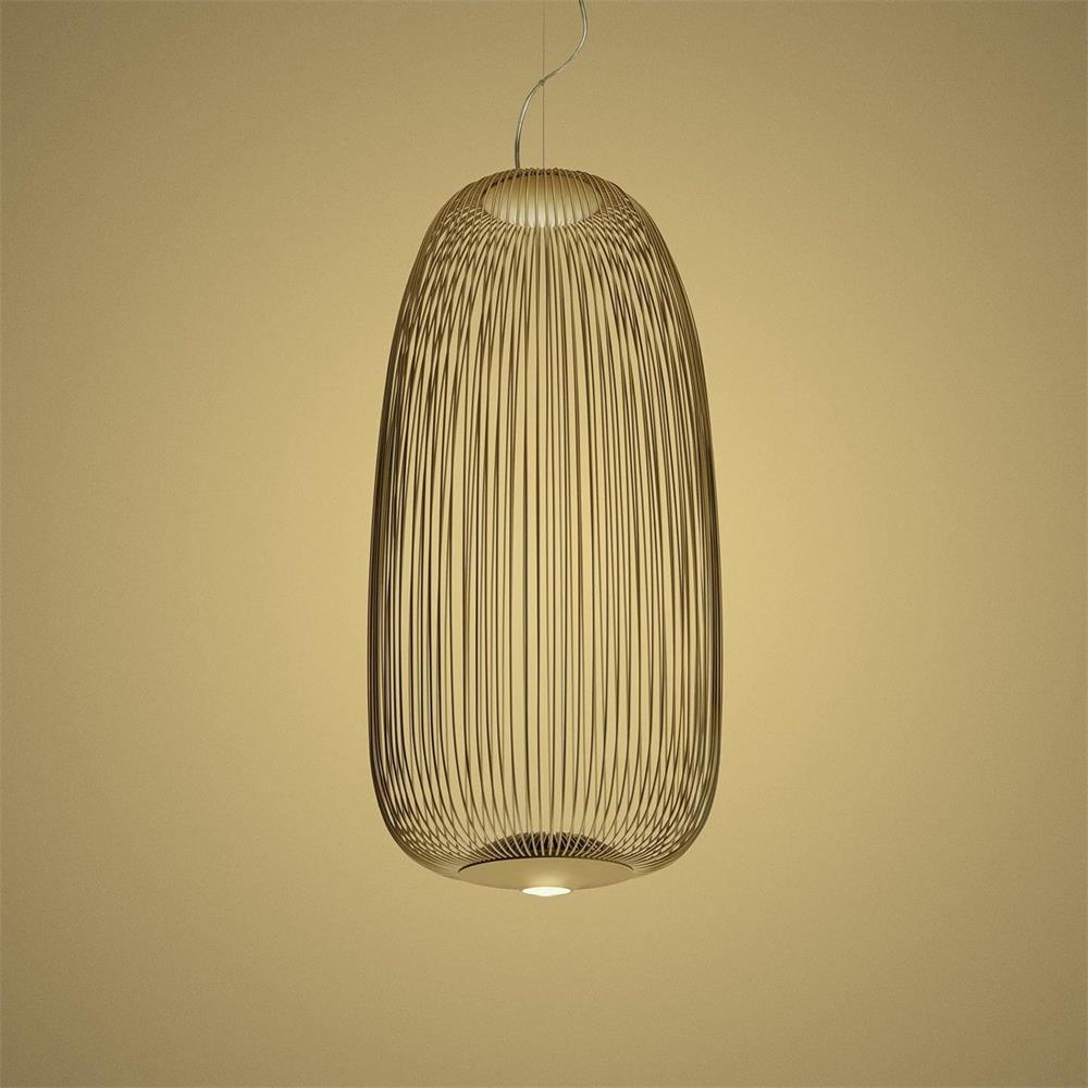 The tall oval wire-cage Clérachic pendant in a gold finish against a warm yellow backdrop.