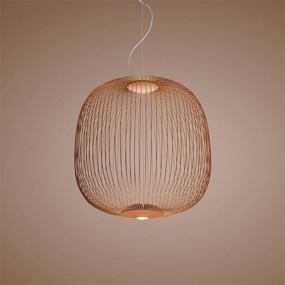The wide, rounded wire-cage Clérachic pendant in a copper finish against a soft pink-brown backdrop.