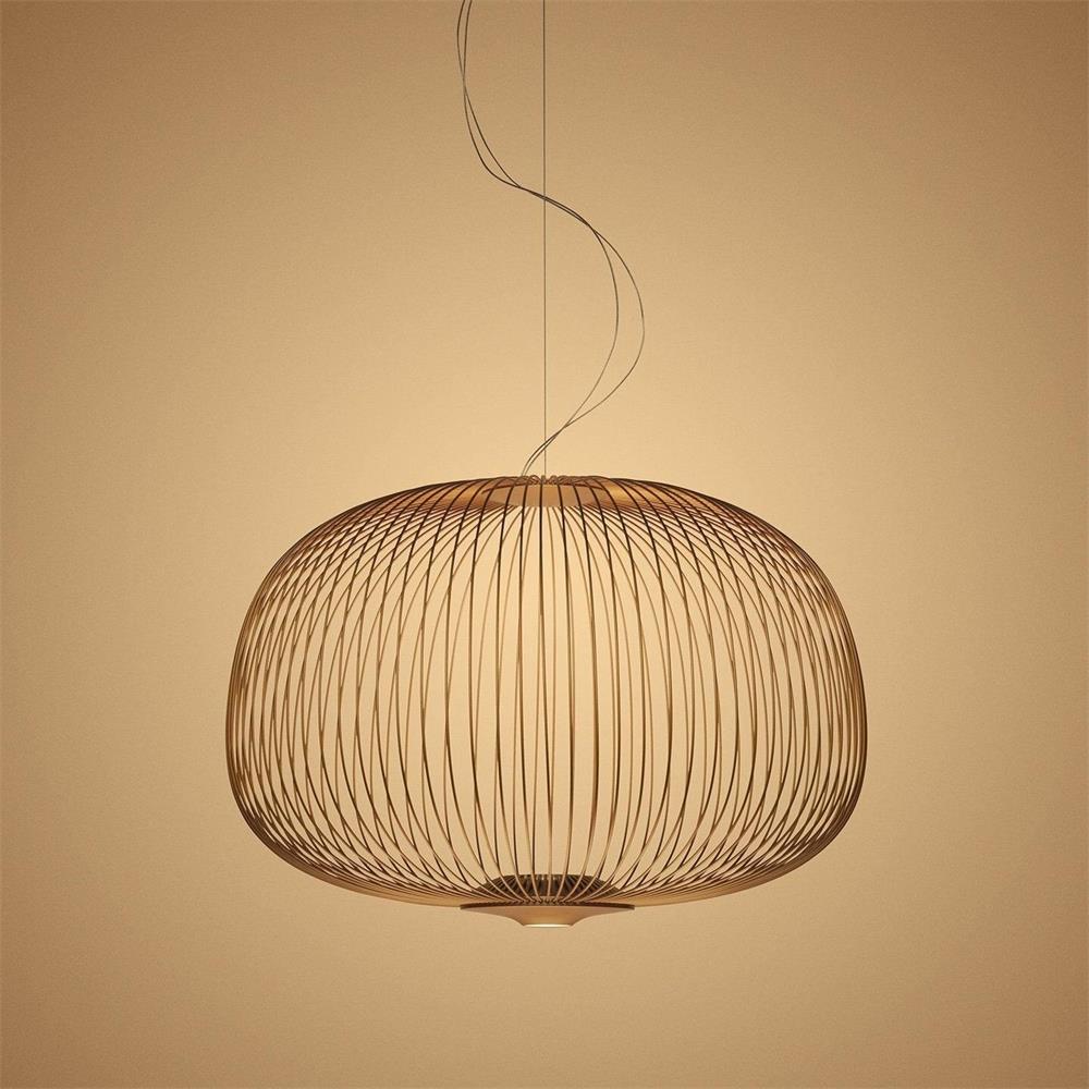 The low, wide drum-shaped wire-cage Clérachic pendant in a copper finish, glowing on an amber backdrop.