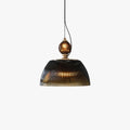 Studio view of the Clérachic ribbed smoked-glass pendant light, showing the brass collar and dome lit warmly from within.