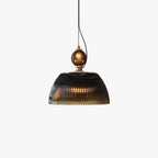 Studio view of the Clérachic ribbed smoked-glass pendant light, showing the brass collar and dome lit warmly from within.