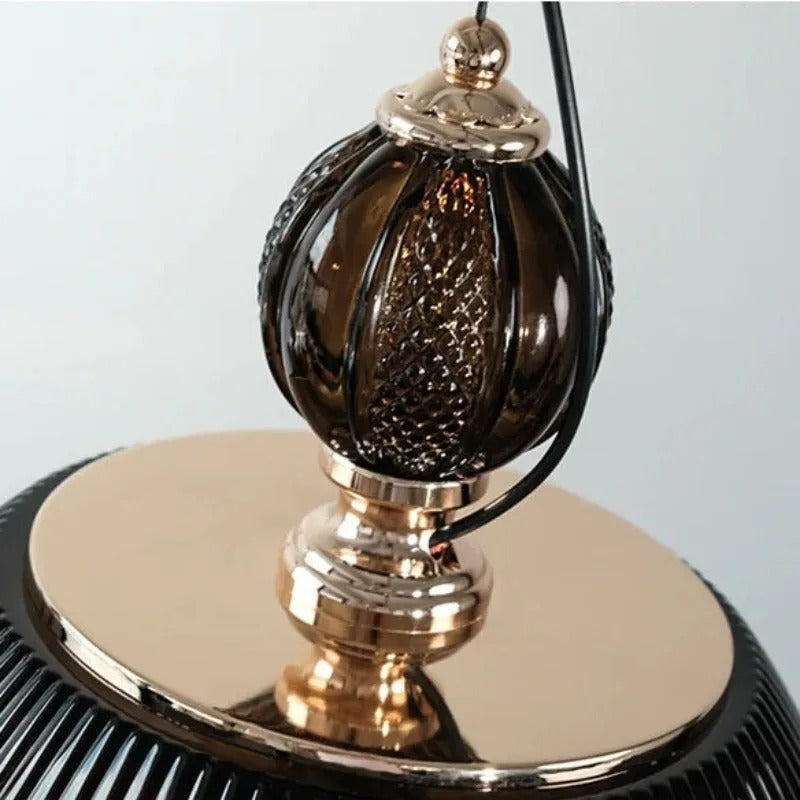 Close-up of the faceted amber glass finial on the Clérachic pendant light, showing the brass fittings above the ribbed shade.