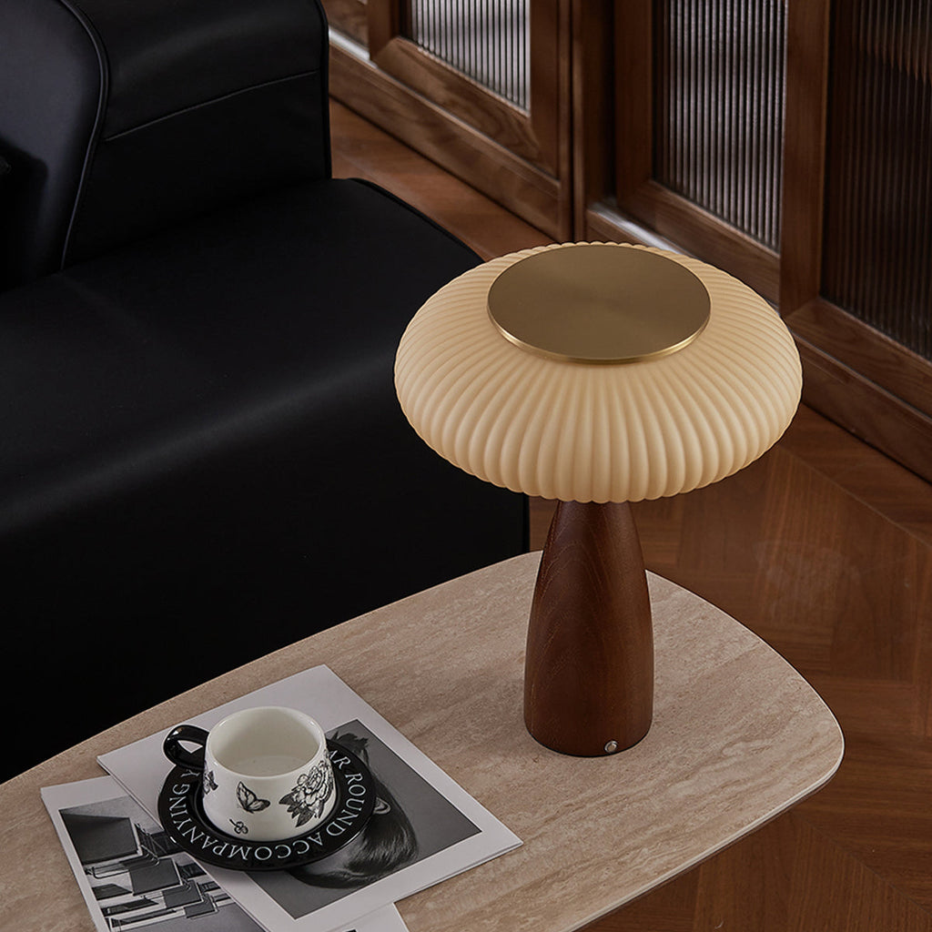 High angle on the brass-topped shade of this Clérachic lamp on a travertine-look table, with a patterned cup on magazines.