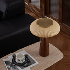 High angle on the brass-topped shade of this Clérachic lamp on a travertine-look table, with a patterned cup on magazines.