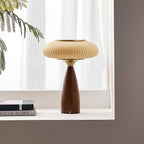 Clérachic table lamp on a white window ledge with stacked books, the sheer curtains and a fern frond behind it.